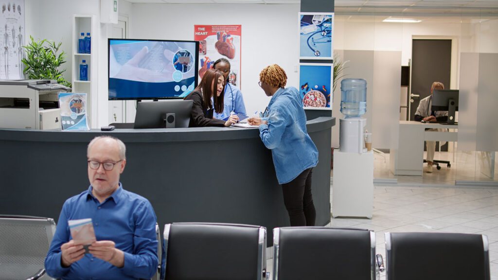 medical office with a man waiting and a women filling out forms at the front desk